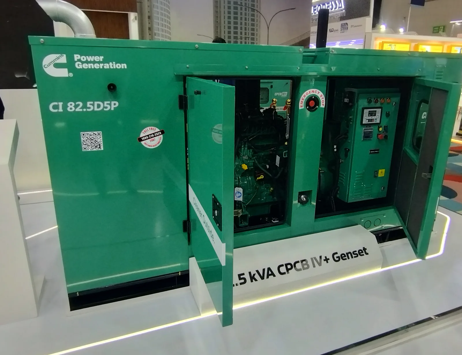 Green Cummins silent canopy generator with its doors open, showing the engine and control panel