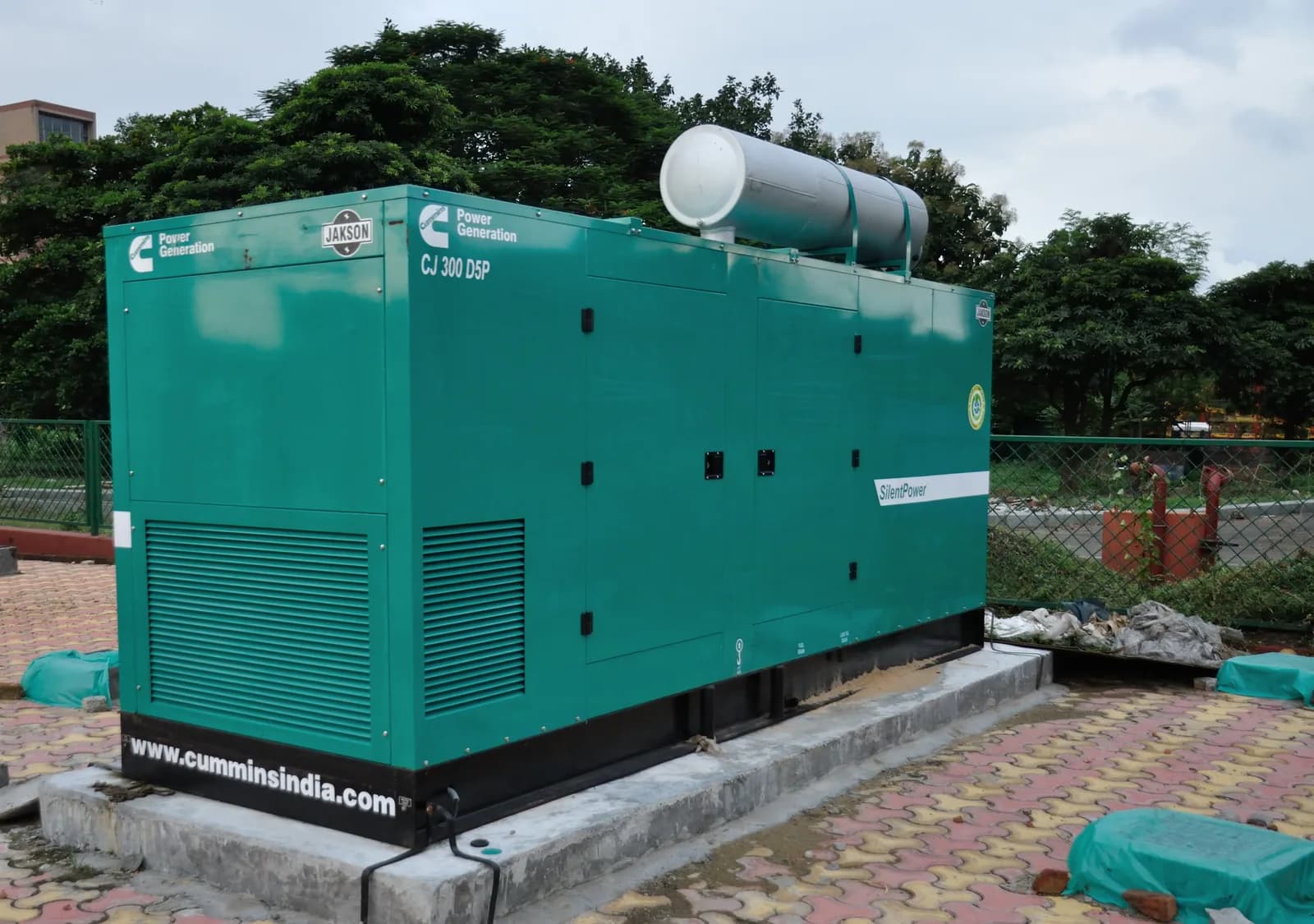 Green Cummins silent canopy generator installed outdoors on a concrete plinth